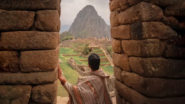 Viajero bajo una portada inca frente a Huayna Picchu