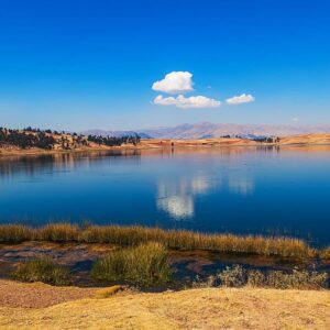 Vista panorámica de la Laguna de Huaypo con reflejo del cielo azul durante el tour en cuatrimoto en Cusco.