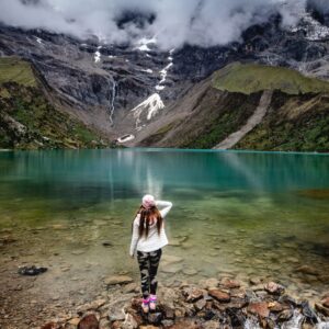 Uma turista contemplando as águas turquesas da Laguna Humantay sob o nevado Salkantay em Cusco, Peru.