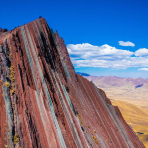 Panoramic view of the colorful peaks and mineral stripes of Palccoyo Mountain under a clear blue sky in Cusco, Peru.